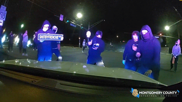Footage captures officer ensconced in vehicle while vandals break windshield