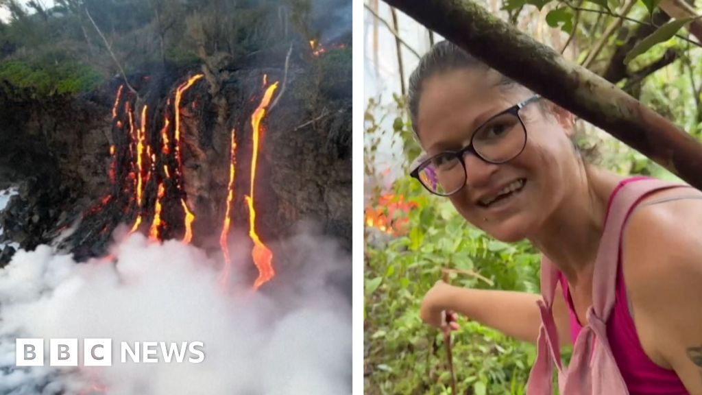 [Local woman stands near lava flow during volcanic eruption on Reunion Island.