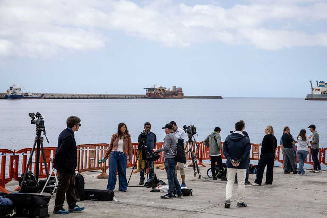 TENERIFE, SPAIN - MAY 09: Members of the press report from an expected reception point for passengers from the MV Hondius at the Granadilla Port on May 09, 2026 in Tenerife, part of the Canary Islands, Spain. The cruise ship MV Hondius, which had three passengers die from Hantavirus last month and eight more reported cases, is expected to arrive on Sunday May 10 in Tenerife, where the remaining passengers will be repatriated to their respective countries. At a press conference this week, representatives of the World Health Organization (WHO) emphasized the outbreak of this rare virus did not constitute a pandemic, but it has stirred anxieties in the Canary Islands and elsewhere.